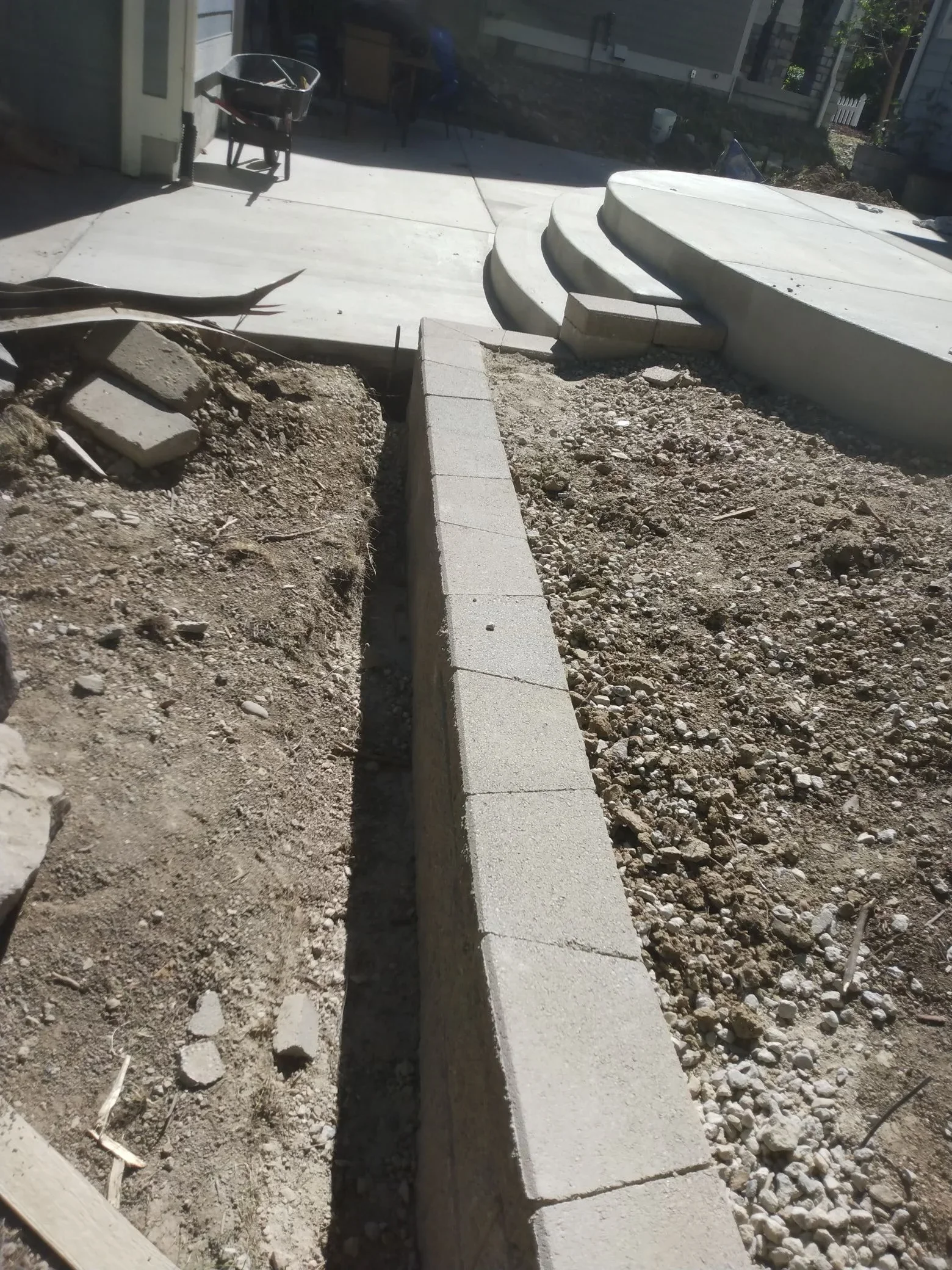 Concrete pathway with center drainage channel, gravel base, and concrete edging during installation
